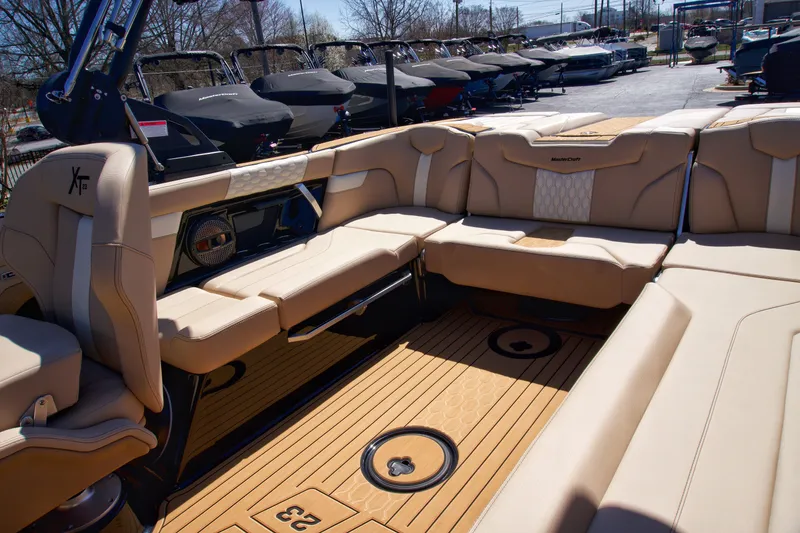 Slide: The Image of 2025 MasterCraft XT23 boat interior with tan seating and wood flooring. - 10