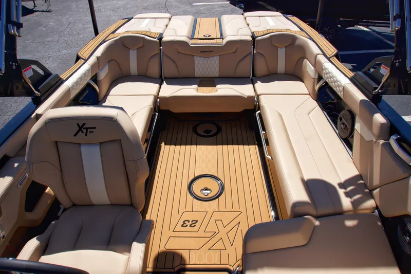 Slide: The Image of 2025 MasterCraft XT23 boat interior with luxurious tan seating and teak flooring. - 13
