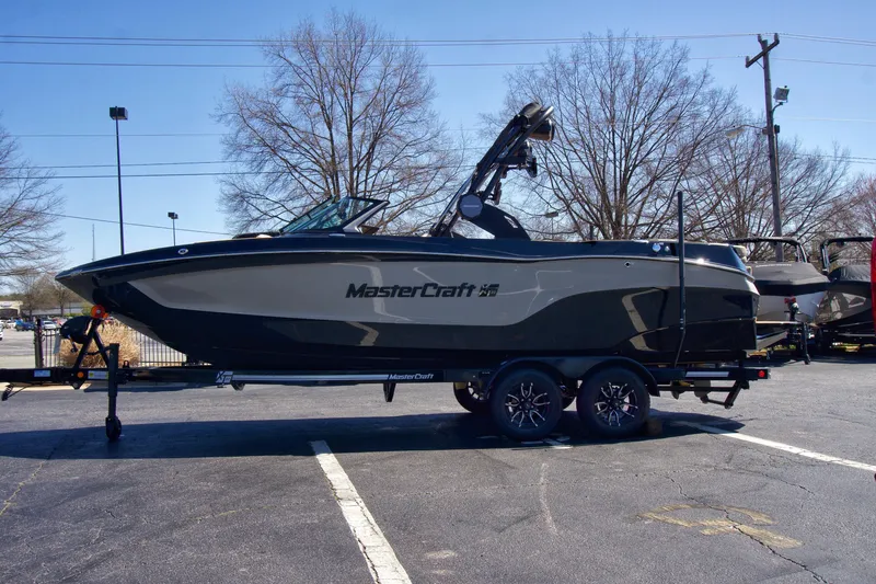 Slide: The Image of 2025 MasterCraft XT23 boat on trailer in parking lot, side view. - 4