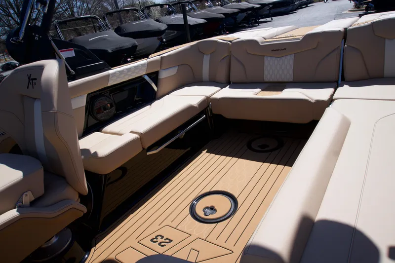 Slide: The Image of 2025 MasterCraft XT23 boat interior with beige seating and teak flooring. - 9