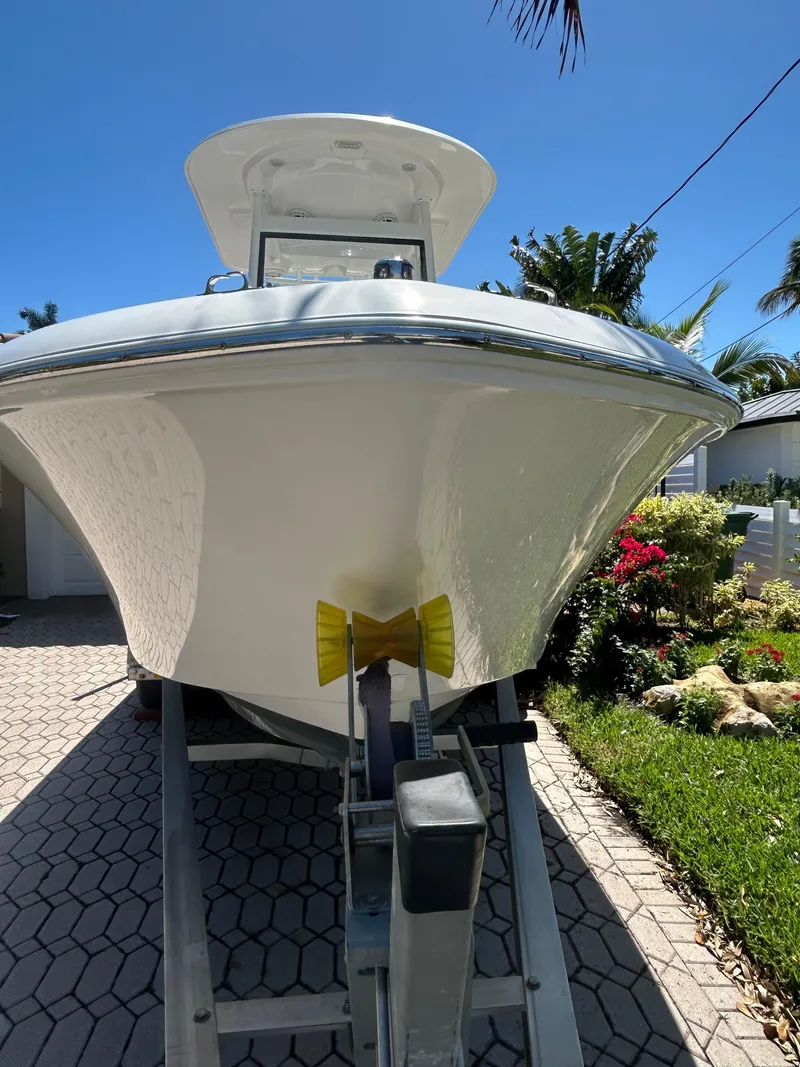 Slide: The Image of 2023 Release 210 RX boat on trailer, parked in sunny driveway with lush greenery. - 14