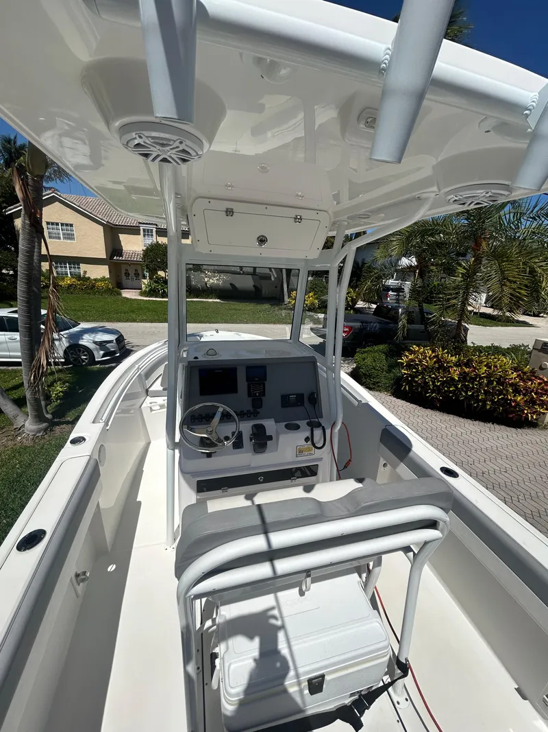 Slide: The Image of 2023 Release 210 RX boat with modern console and seating, parked outdoors. - 27