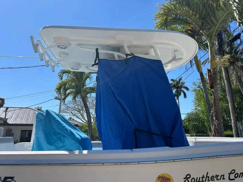 Slide: The Image of 2023 Release 210 RX boat with blue cover, palm trees in background. - 40