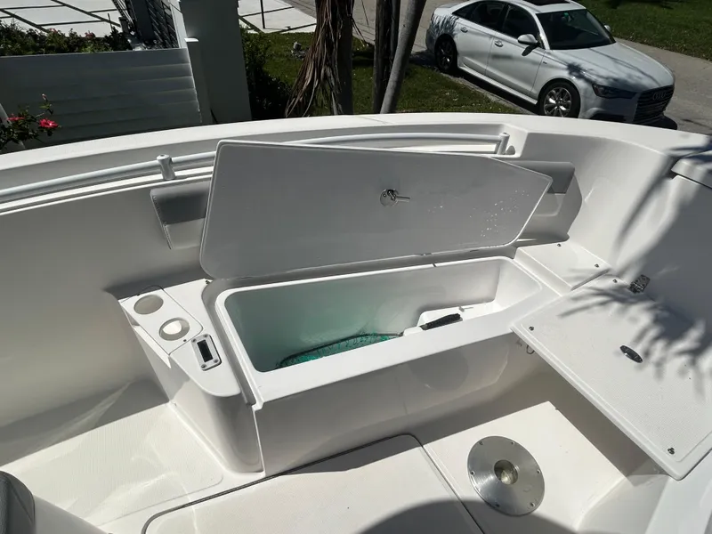 Slide: The Image of Open storage compartment on 2023 Release 210 RX boat, with nearby parked car. - 42