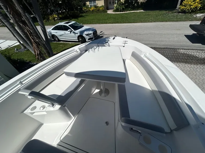 Slide: The Image of 2023 Release 210 RX boat with seating and table, parked near a residential street. - 44