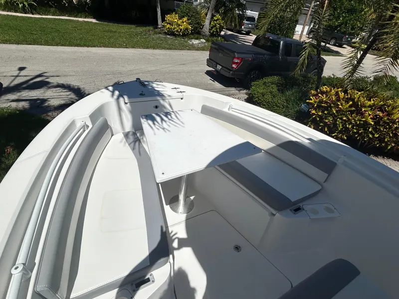 Slide: The Image of 2023 Release 210 RX boat with seating and table, parked near a truck and greenery. - 45