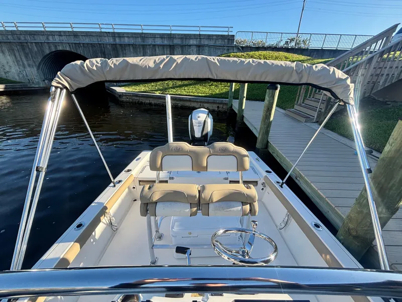 Slide: The Image of 2017 Key West 230 Bay Reef boat docked near a bridge, featuring a bimini top. - 7