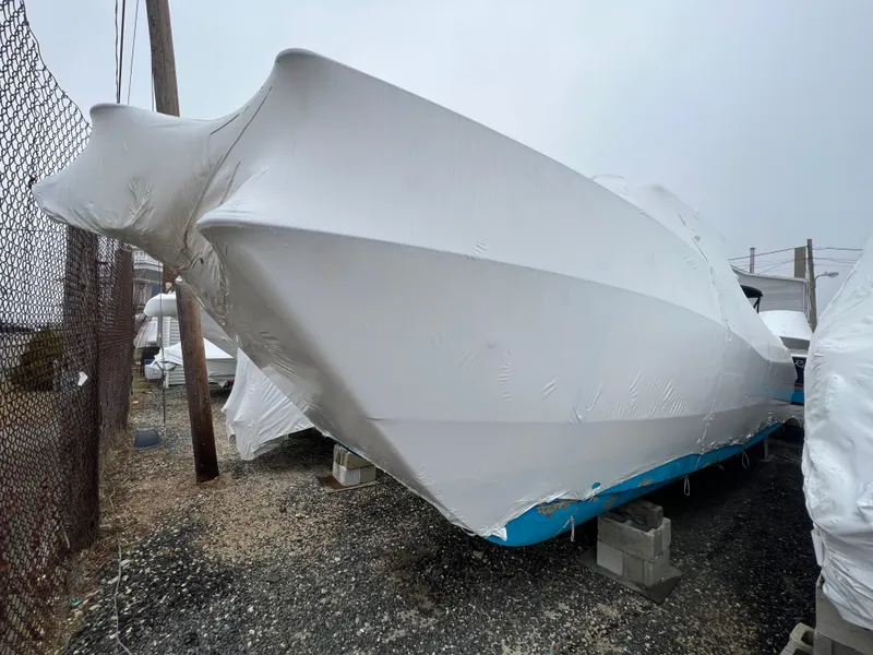 Slide: The Image of 1998 World Cat 270TE boat covered in protective wrap, stored on blocks outdoors. - 4