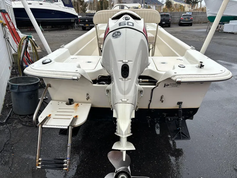 Slide: The Image of 2014 Carolina Skiff JVX18CC boat with outboard motor and swim ladder, parked on asphalt. - 12
