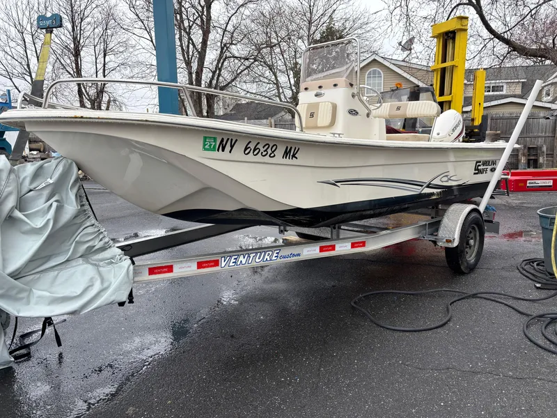 Slide: The Image of 2014 Carolina Skiff JVX18CC boat on trailer, parked outdoors, with visible registration number. - 2