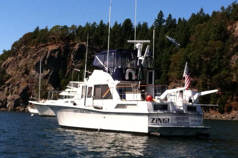 Slide: The Image of 1971 Uniflite 42 DC boat anchored near rocky shoreline with trees. - 1