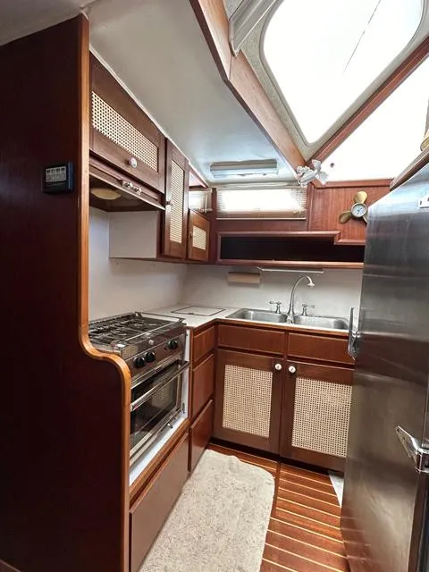 Slide: The Image of 1971 Uniflite 42 DC yacht kitchen with wood cabinetry, stove, sink, and skylight. - 11