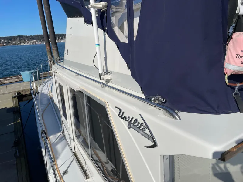 Slide: The Image of 1971 Uniflite 42 DC yacht docked, featuring sleek design and navy blue canopy. - 8