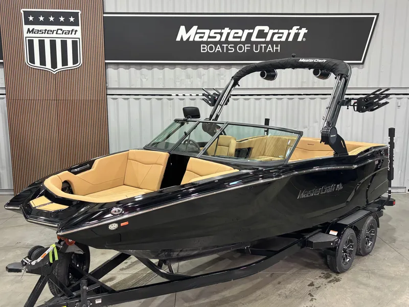 The Image of 2025 MasterCraft NXT22 boat in showroom, black exterior, tan interior, displayed at MasterCraft Boats of Utah. - 0