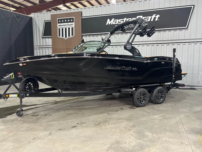 Slide: The Image of 2025 MasterCraft NXT22 boat in showroom, sleek black design on trailer. - 2