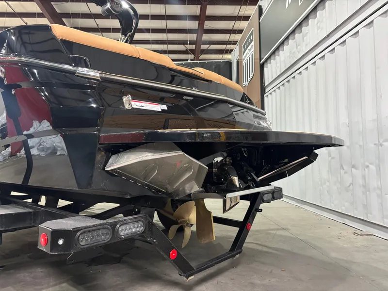 Slide: The Image of 2025 MasterCraft NXT22 boat rear view in a warehouse, showcasing propeller and trailer. - 4