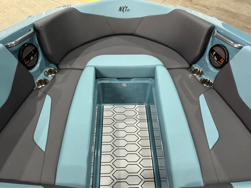 Slide: The Image of 2025 MasterCraft NXT23 boat interior with blue and gray seating and hexagonal floor design. - 11