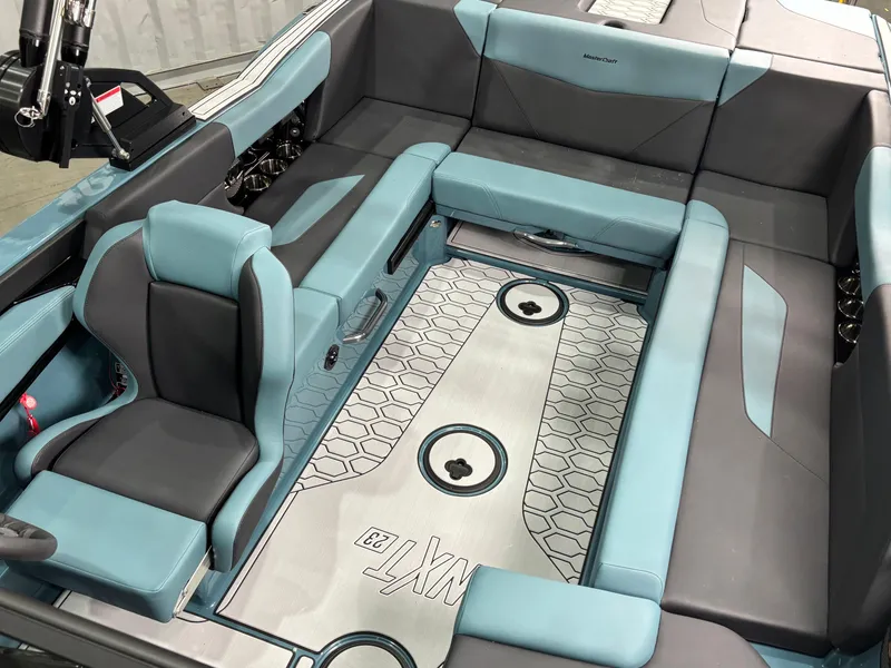 Slide: The Image of 2025 MasterCraft NXT23 boat interior with teal and gray seating, modern design. - 12