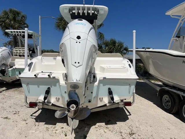 Slide: The Image of 2025 Key West 239 FS boat, rear view with outboard motor, parked on sandy ground. - 2