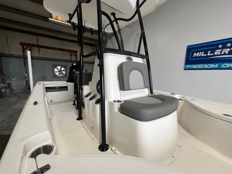 Slide: The Image of 2024 Sea Born FX 21 BAY boat interior with seating and console, in a showroom setting. - 7