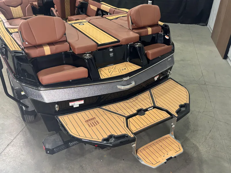 Slide: The Image of 2025 MasterCraft XT24 boat with brown seating and teak deck, rear view. - 7