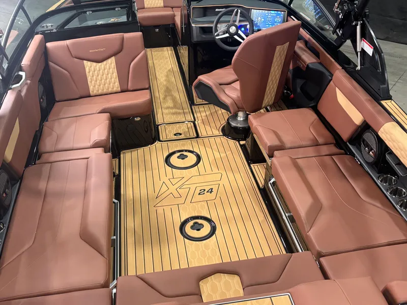 Slide: The Image of 2025 MasterCraft XT24 boat interior with luxurious brown seating and sleek dashboard design. - 9