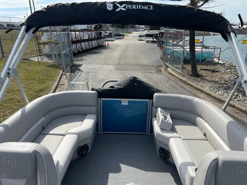 Slide: The Image of 2025 Godfrey Xperience Split Bench boat with spacious seating and canopy, docked by the water. - 11