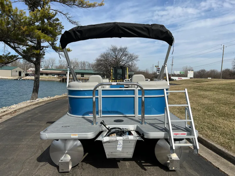 Slide: The Image of 2025 Godfrey Xperience Split Bench pontoon boat by a lakeside, featuring a blue exterior. - 5