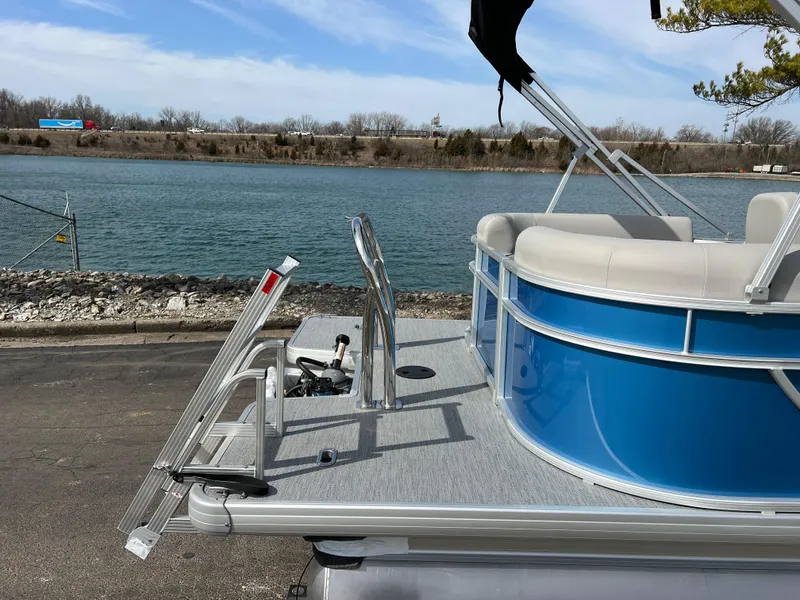 Slide: The Image of 2025 Godfrey Xperience Split Bench pontoon boat by a lakeside. - 6