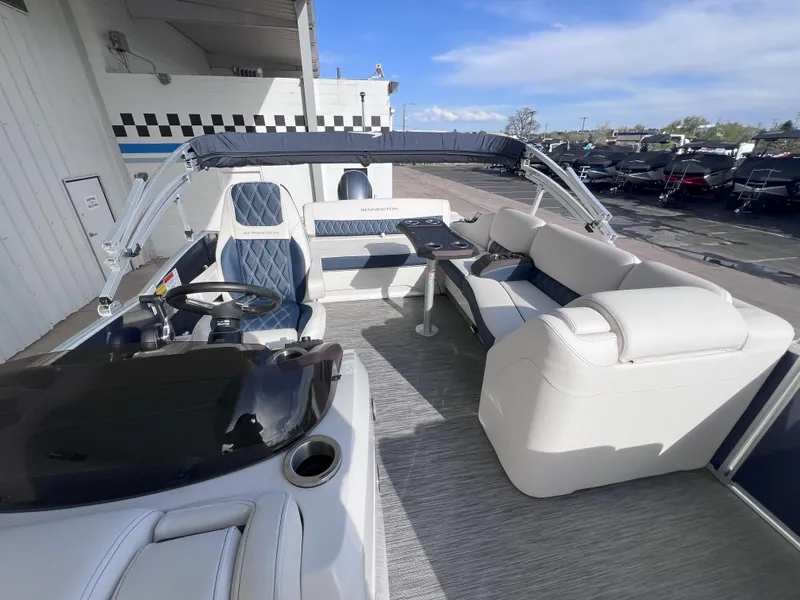 Slide: The Image of 2022 Bennington 25RSB pontoon boat interior with seating and helm, docked outdoors. - 13