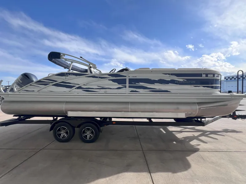 Slide: The Image of 2022 Bennington 25RSB pontoon boat on trailer under a clear blue sky. - 4