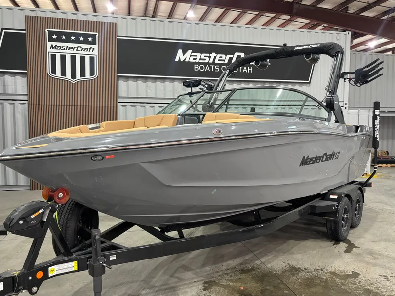 Slide: The Image of 2025 MasterCraft XT23 boat in showroom, gray exterior, on trailer. - 2