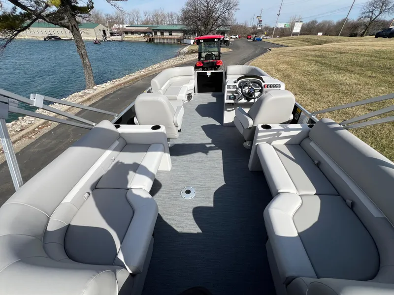 Slide: The Image of 2025 Godfrey Xperience Split Bench boat with spacious seating, docked by a scenic lakeside. - 14