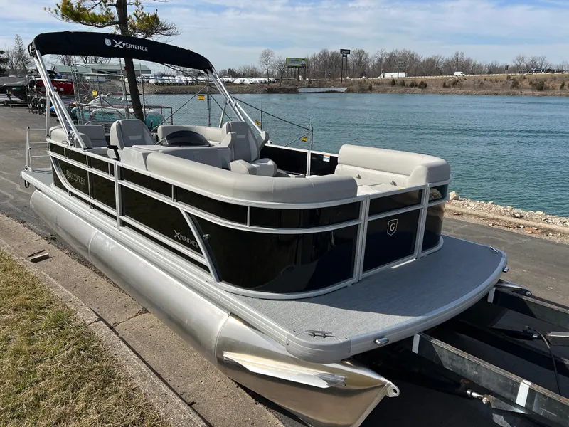 Slide: The Image of 2025 Godfrey Xperience Split Bench pontoon boat docked by a serene river. - 2