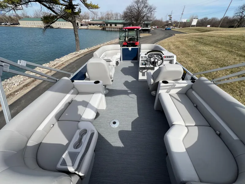 Slide: The Image of 2025 Godfrey Xperience Split Bench pontoon boat with spacious seating by a lakeside. - 12