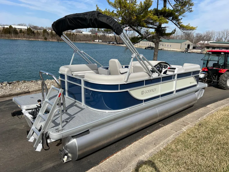 Slide: The Image of 2025 Godfrey Xperience Split Bench pontoon boat docked by a serene lake. - 4