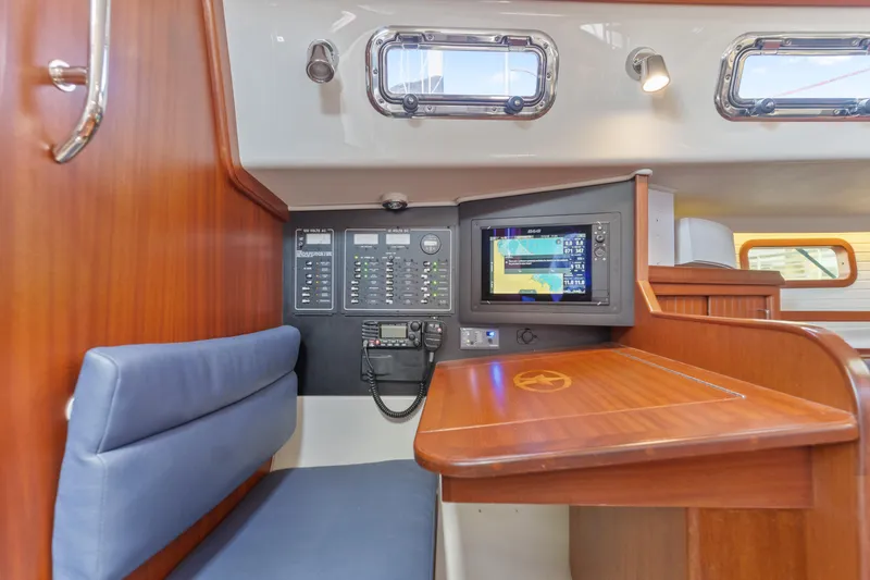 Slide: The Image of Navigation station inside 2015 Blue Jacket 40 sailboat, featuring control panel and seating. - 13