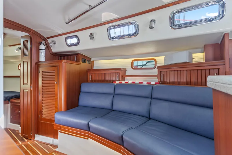 Slide: The Image of Interior of 2015 Blue Jacket 40 sailboat with blue seating and wooden cabinetry. - 17