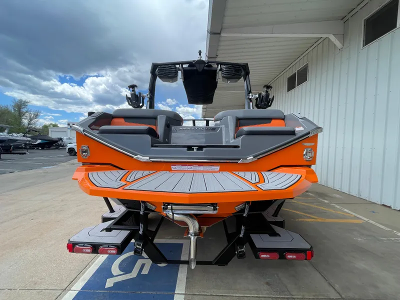 Slide: The Image of 2023 Nautique Super Air Nautique G21 boat, orange and gray, rear view at dock. - 4