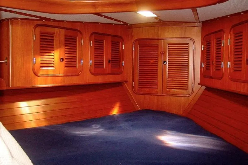 Slide: The Image of 1986 Mason 33 yacht interior with wooden cabinets and blue bedding. - 9