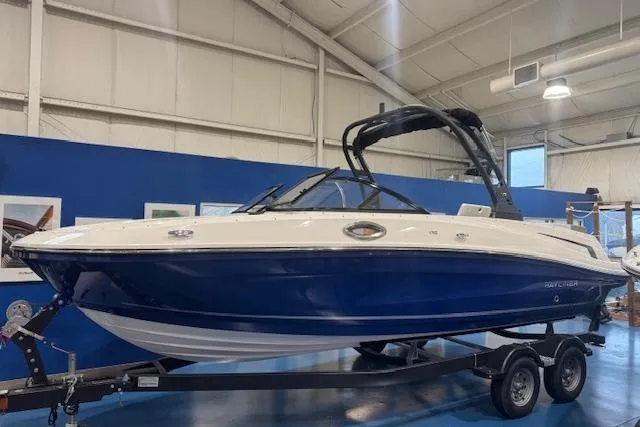 The Image of 2025 Bayliner VR6 Bowrider I/O boat in showroom, blue and white design on trailer. - 0