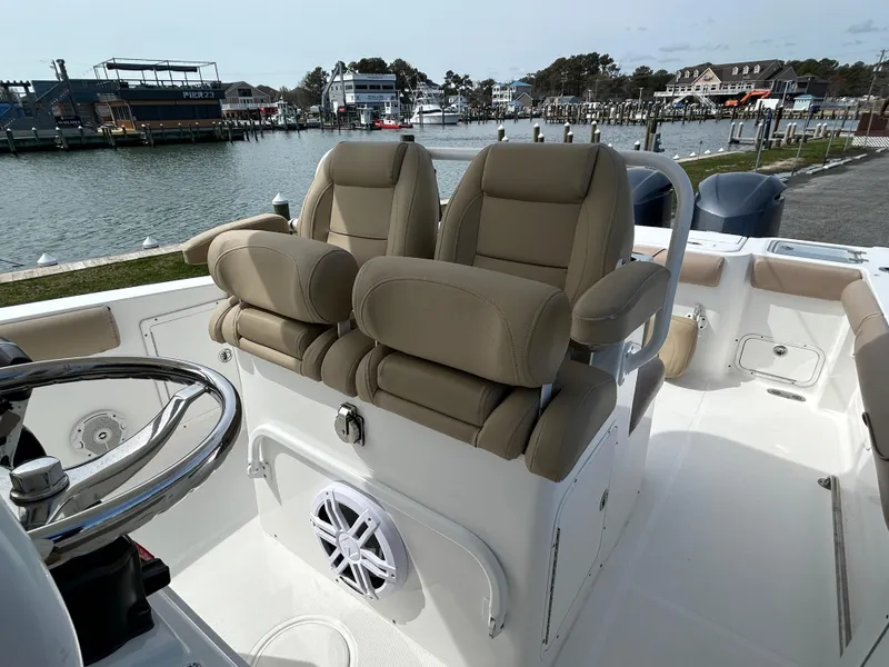 Slide: The Image of 2015 Sea Hunt Gamefish 30 boat interior with dual seats and steering wheel, docked by the water. - 12