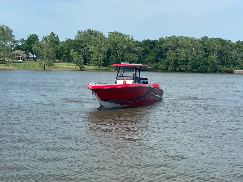 Slide: The Image of Red 2022 Fountain 38 SC boat cruising on a calm lake with trees in the background. - 10