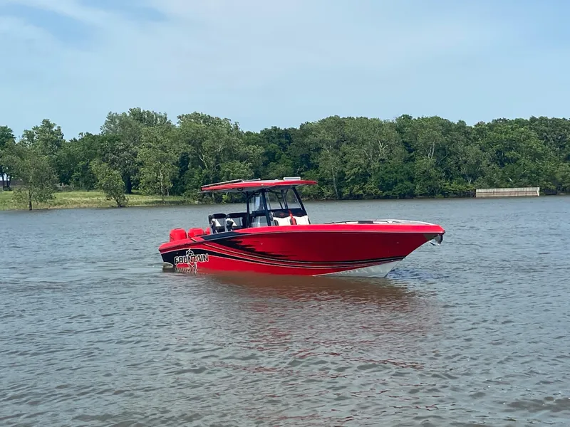 Slide: The Image of Red 2022 Fountain 38 SC boat cruising on a calm lake with trees in the background. - 7