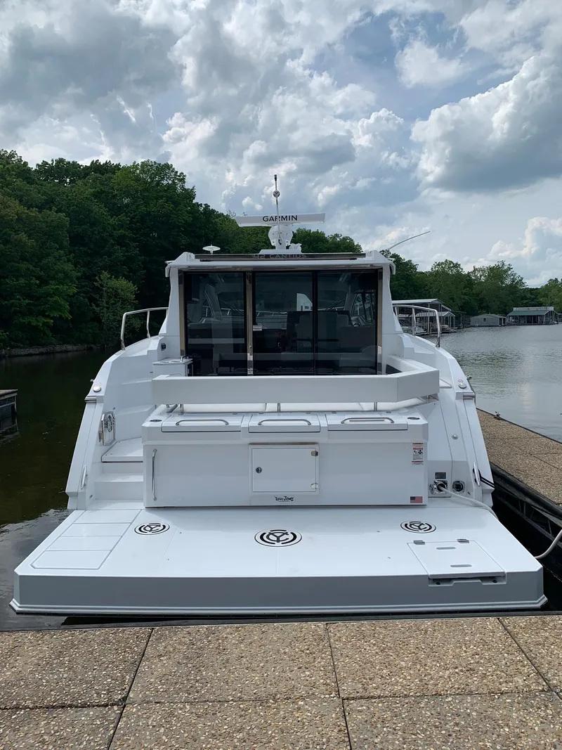Slide: The Image of 2019 Cruisers Yachts 42 Cantius docked by a serene lake under a cloudy sky. - 19