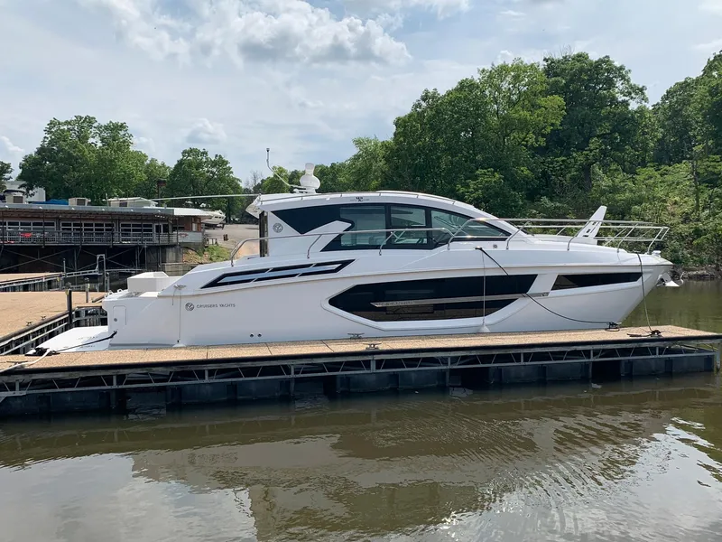 Slide: The Image of 2019 Cruisers Yachts 42 Cantius docked on a calm river, surrounded by lush greenery. - 7