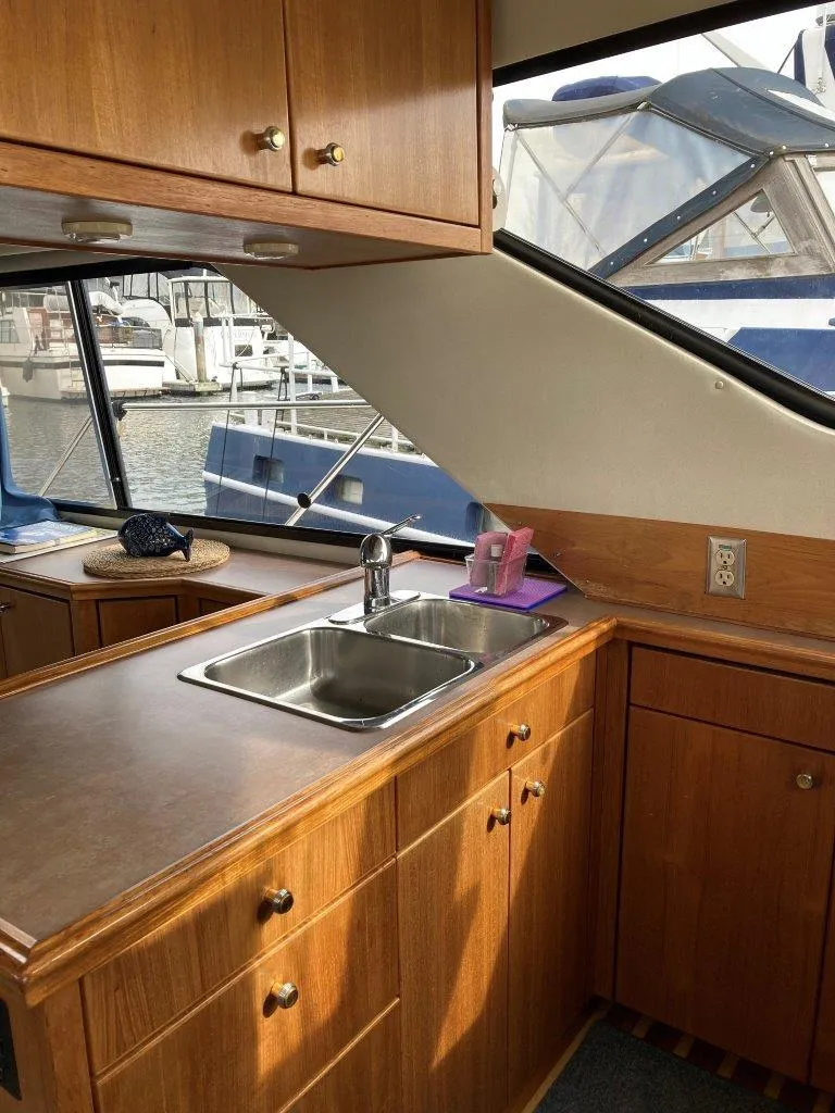 Slide: The Image of 1996 Bayliner 3788 Command Bridge Motoryacht kitchen with wooden cabinets and marina view. - 25