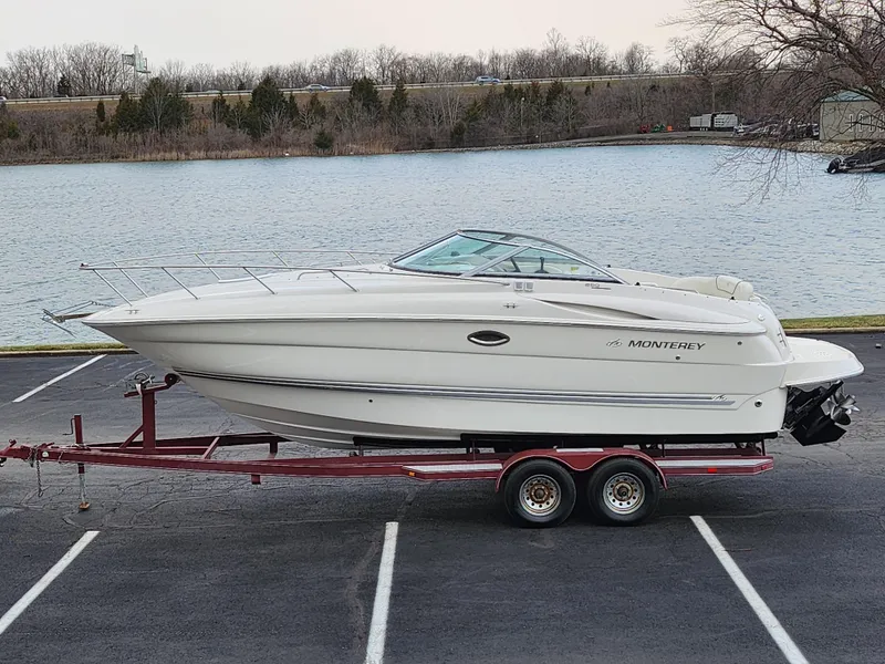 Slide: The Image of 2007 Monterey 250 Cruiser boat on trailer by a lake. - 0