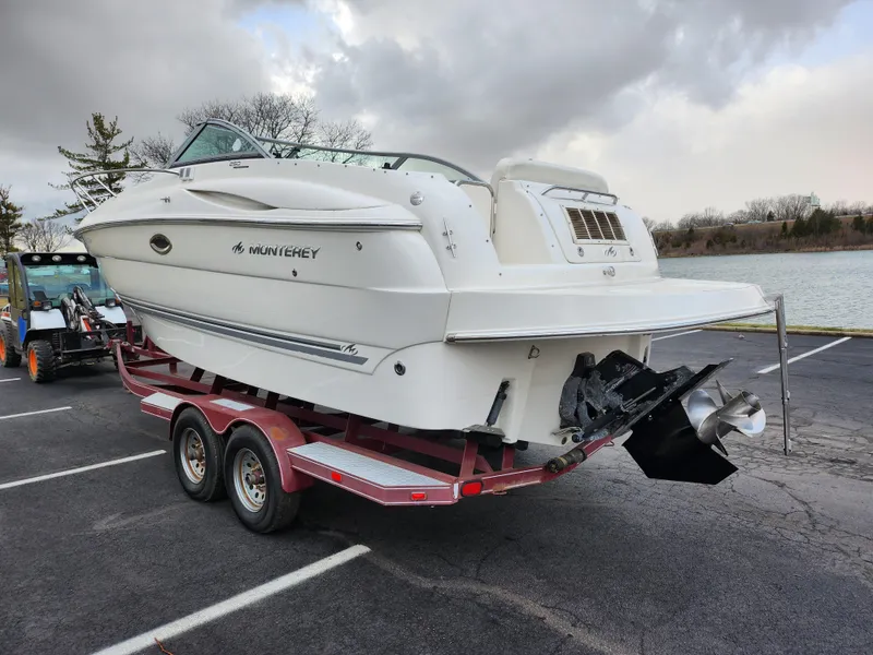 Slide: The Image of 2007 Monterey 250 Cruiser boat on trailer near a lake, overcast sky. - 1