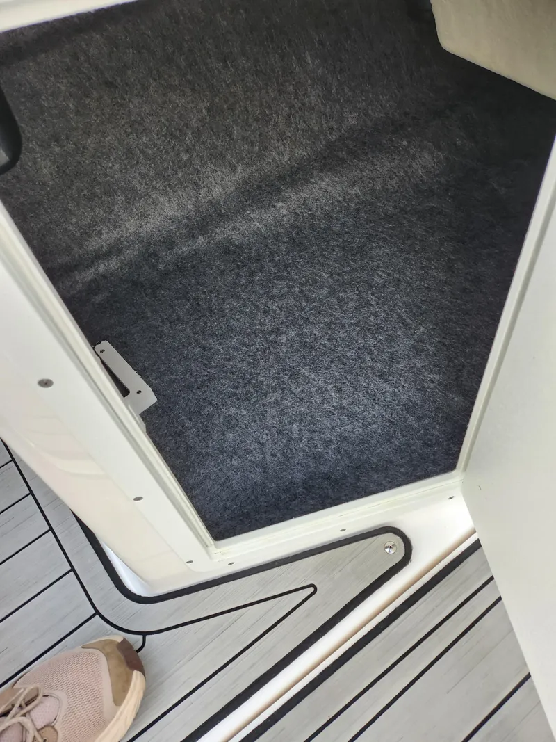 Slide: The Image of 2017 Yamaha Boats AR190 storage compartment with carpeted interior and deck flooring. - 15